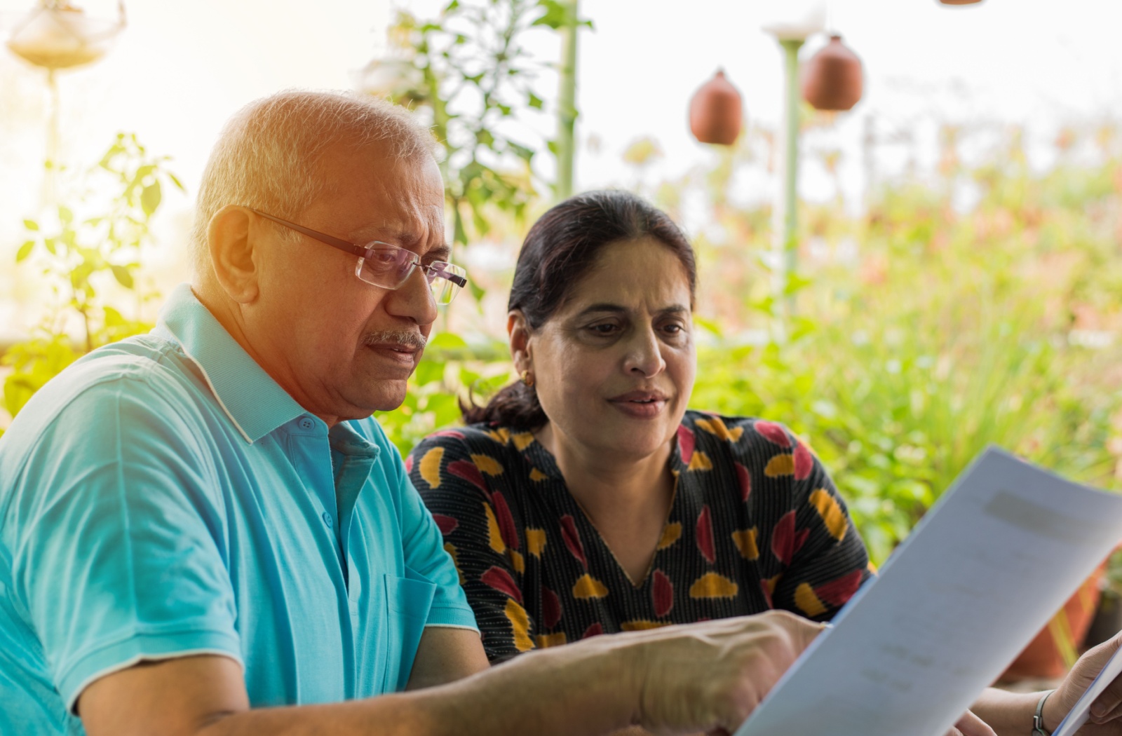 Senior couple reviewing Power of Attorney paperwork after dementia diagnosis. They are outside with the sun setting on the left.