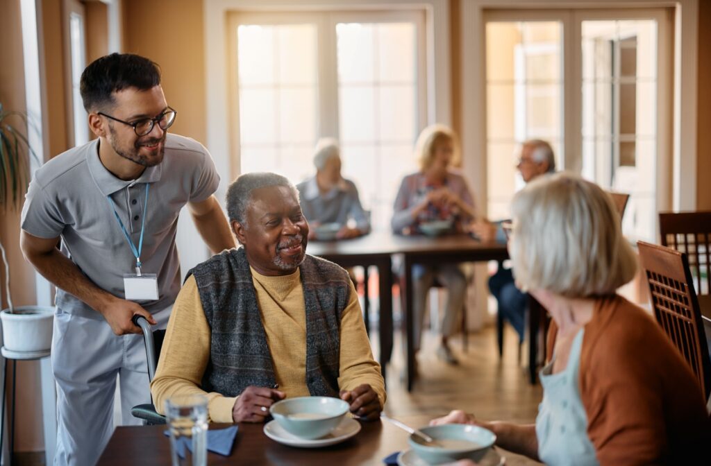 A senior who uses a wheelchair enjoying lunch with peers at an assisted living community