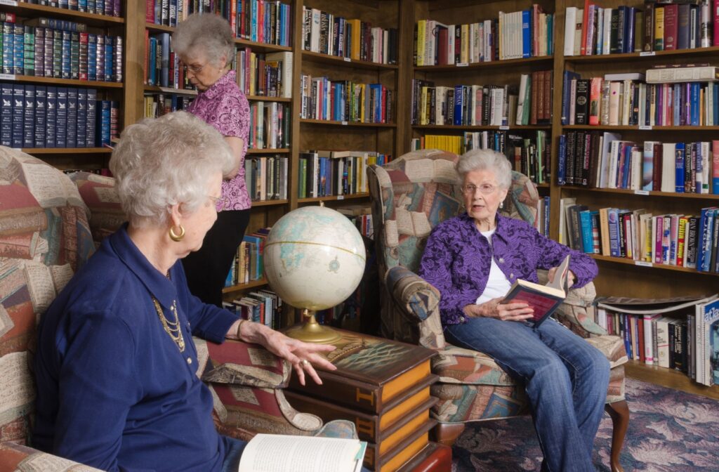 Senior women enjoying reading some books in Peregrine Cheektowaga's library.