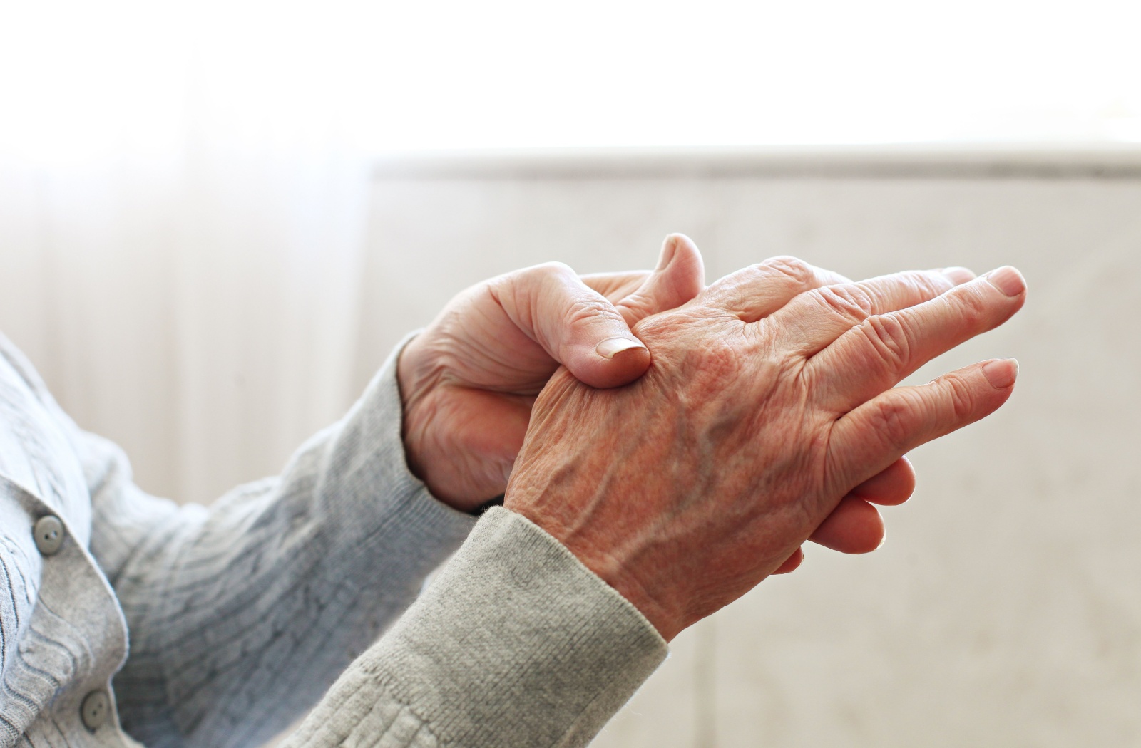 A close-up of a senior's hands as they try to mimic hand motions by a caretaker during the Interlocking Finger Test.