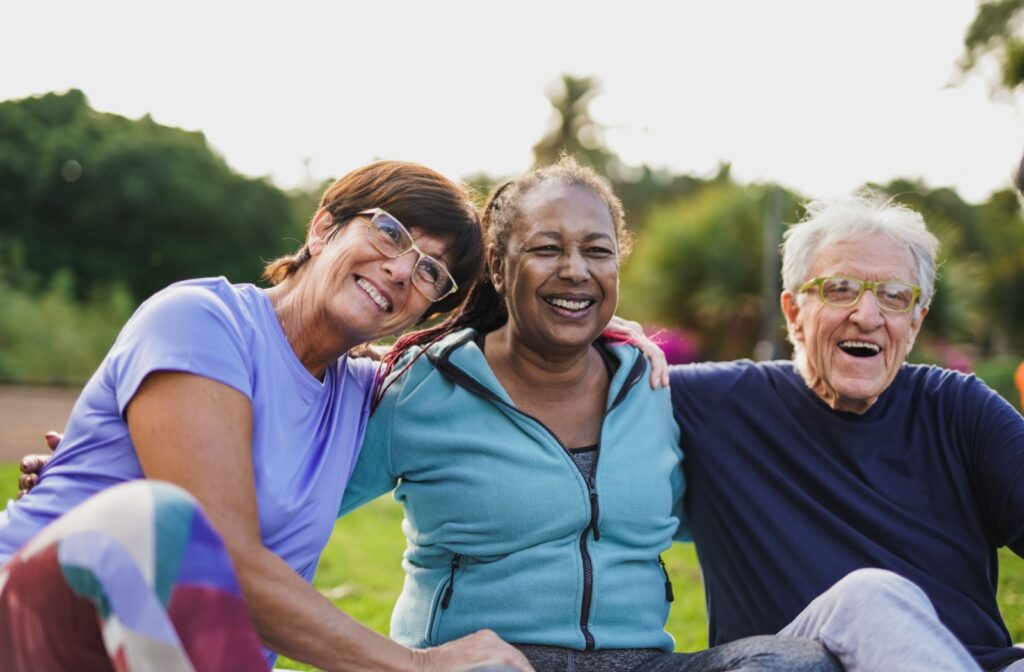 Three seniors sitting outdoors wrap their arms around each other, delighting in the outdoor air and the companionship
